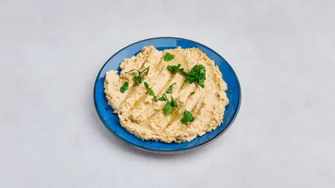 Hummus z natką pietruszki na niebieskim talerzu